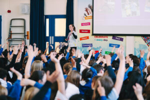Children with their hands up with an presentation in front of them
